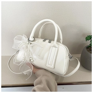 Vue détaillée du sac Boston blanc avec nœud en tulle et breloque en perles élégante