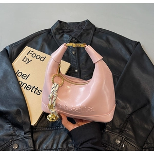 Pink dumpling handbag detail featuring 3D embossed logo and decorative gold bell charm