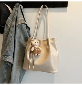 Detailed view of glossy beige tote bag with cute bear pendant and spacious interior