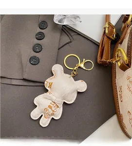 Detail of bear-shaped leather bag charm with gold metal clasp on a gray blazer