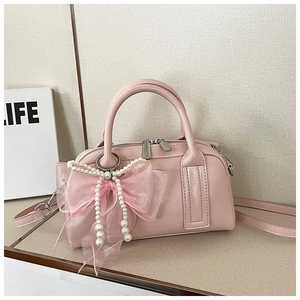 Détail du sac Boston en cuir verni rose avec nœud en tulle et pendentif en perles