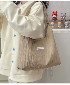 Detailed shot of pleated khaki tote bag with Duociyuan Bag label on white background