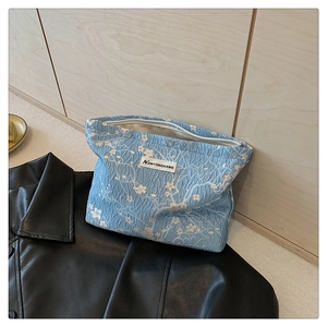 Detail of light blue jacquard texture and white floral pattern on a canvas makeup bag