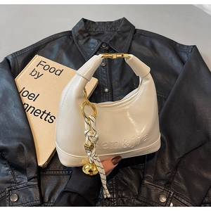 Close-up of beige glossy dumpling bag with embossed logo and golden metal hardware details