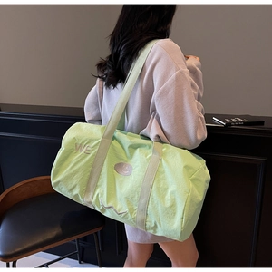 Dettaglio borsa da viaggio in tela verde chiaro con ricamo WE e tracolla larga