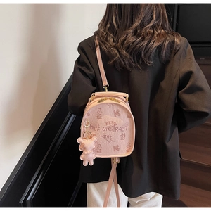 Detail of pink mini backpack with cartoon prints and plush bear pendant accessory