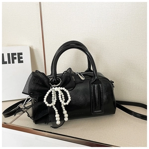 Détail du sac Boston en cuir brillant noir avec charm nœud en perles et doubles poignées