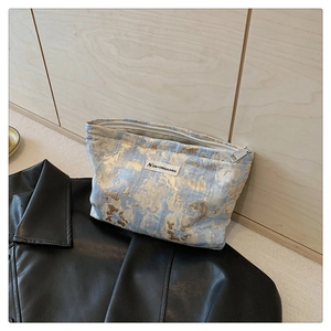 Detail of blue and gold jacquard weave texture and zipper on the small makeup bag