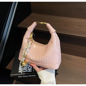 Detail of pink hobo bag with gold hardware, silk scarf, and brand logo embossing