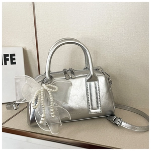 Vue détaillée du sac Boston argenté avec nœud en résille, perles et texture métallique