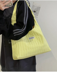 Detail of lemon yellow pleated tote bag showing fabric texture and brand label