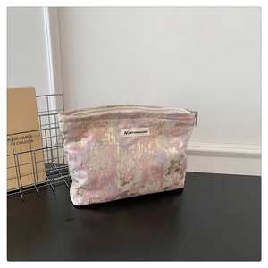 Close-up of woven fabric makeup bag showing embossed pink and gold floral textures