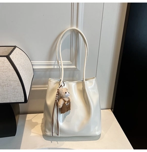 Close-up of minimalist white glossy tote bag with a cute brown teddy bear keychain