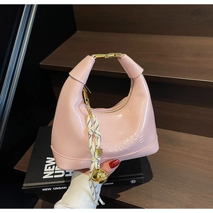 Pink glossy dumpling bag detail with gold metal clasp and decorative bell pendant