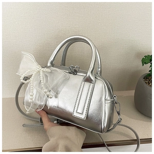Détail du sac Boston argenté avec un nœud en tulle blanc et une chaîne de perles décorative