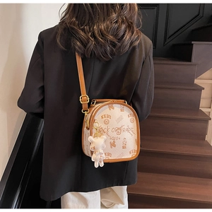 Detail of white vintage backpack with brown trim and cute plush bear charm on back