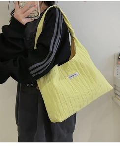 Detail of yellow pleated tote bag with Duociyuan Bag label shown on model shoulder
