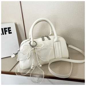 Détail du sac Boston blanc avec nœud en organza perlé et texture en cuir lisse élégante