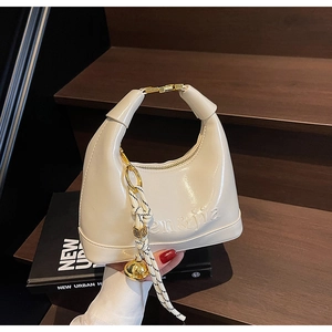 Detailed shot of cream white hobo bag with gold hardware and woven rope charm