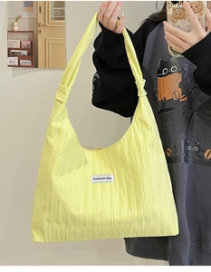 Detail of yellow pleated tote bag with a unique knot strap and brand label