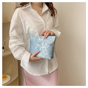 Close-up of light blue textured woven bag with floral patterns and a small label