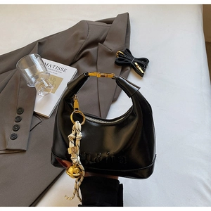 Detail of black crescent handbag featuring letter embossing and golden ring buckle
