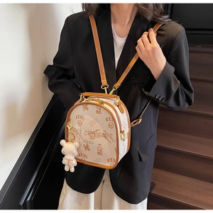 Detail of a mini beige leather backpack with cartoon bear prints and plush charm