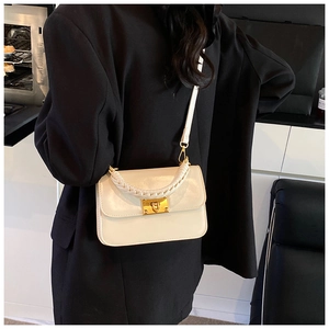 Détail latéral du sac bandoulière blanc en similicuir avec poignée tressée et fermoir