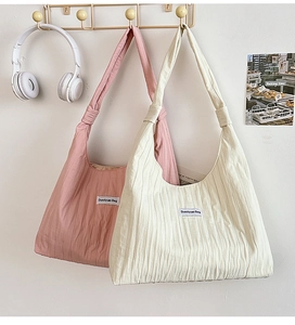 Detail of pleated fabric texture on soft casual tote bags with minimalist logo tags