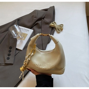 Detail of creamy white dumpling shoulder bag with gold metal buckles and embossed logo