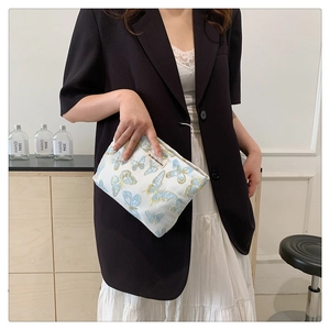 Detail of white canvas pouch featuring elegant blue and gold butterfly embroidery patterns