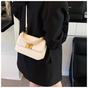 Détail du sac à rabat en cuir blanc avec boucle dorée et poignée tissée sur mannequin