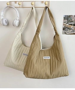 Detail of pleated canvas tote bags in cream and camel with minimalist brand label