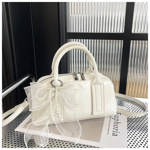 Détail du sac Boston crème avec nœud en organza et perles nacrées sur maille métal