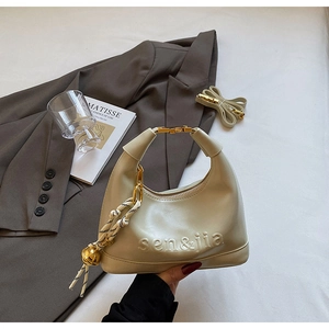 Detail of cream leather pillow bag with embossed lettering and silk scarf accessory