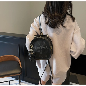 Detail of black pebbled leather mini backpack with bear charm and artistic print