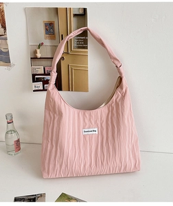 Close-up of pink pleated fabric tote bag with a white minimalist brand label detail