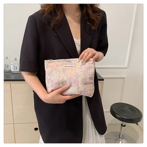 Detailed close-up of a pink woven jacquard pouch held by a model for a lifestyle view