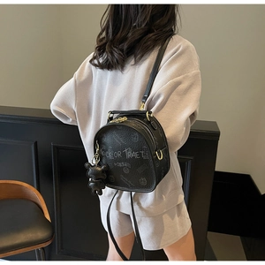 Detail of black pebbled leather backpack featuring graffiti print and a cute bear charm