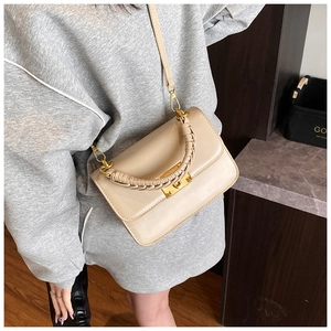 Détail du sac beige avec poignée tressée et fermoir pivotant en métal doré