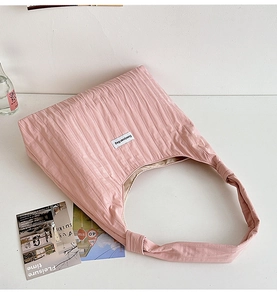 Detail shot of light pink pleated fabric shoulder bag with DuoDuoBag logo on front