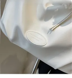 Vue détaillée de la texture en similicuir blanc et logo ovale embossé sur le sac cabas