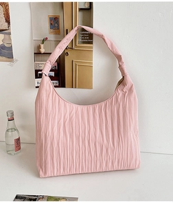 Detailed macro view of the pleated texture and curved wide strap on this pink hobo bag