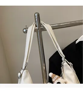 Détail d'un sac à épaule en cuir blanc avec large bandoulière et pendentif en peluche marron