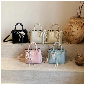 Detail of five-color PU leather bucket bags with pearl charms and bow accents
