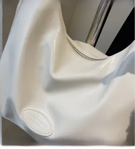 Gros plan d'un sac hobo beige montrant la texture du cuir souple et le logo gravé