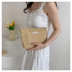 Detail view of a woven small canvas zipper bag with a textured finish and brand label