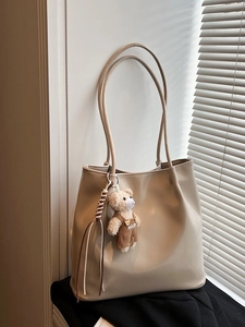 Minimalist beige tote bag in smooth PU leather with cute bear charm for daily commuting