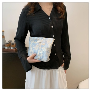 Close-up of blue and gold woven canvas cosmetic bag with aesthetic textured oil painting pattern