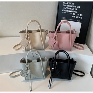 Vue détaillée de quatre sacs à main minimalistes en beige, rose, bleu et noir avec charm